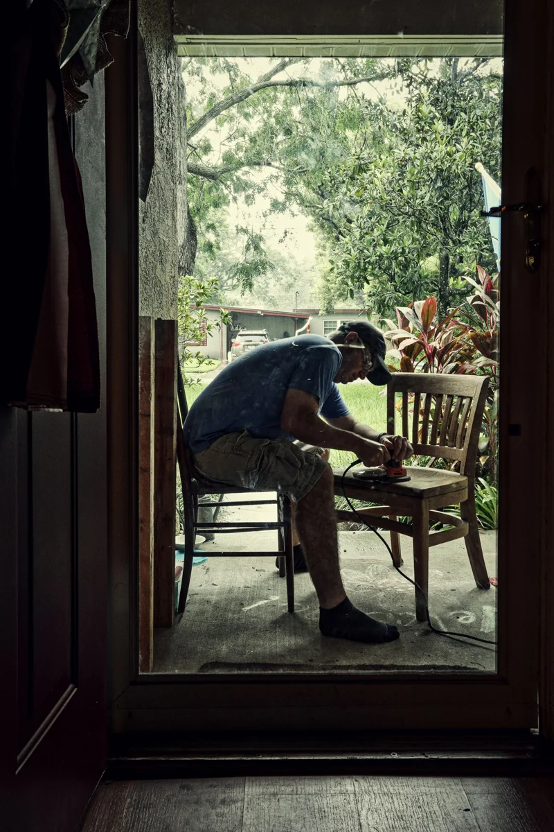 Craftsperson working with wooden chairs.