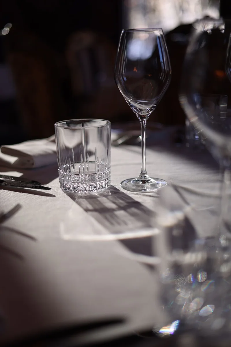 Wine glass and tumbler on a sunlit table.