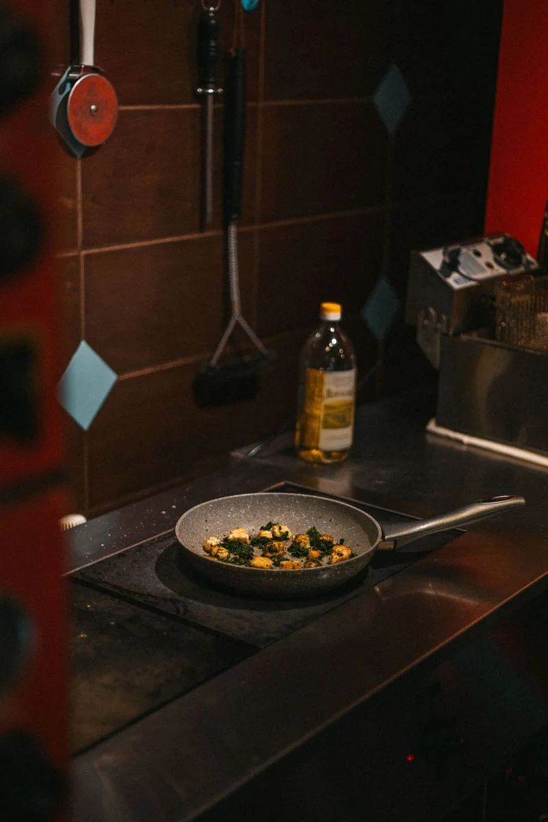 A frying pan with vegetables on a kitchen stove.