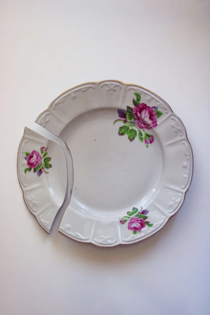A broken floral porcelain plate on a light background.