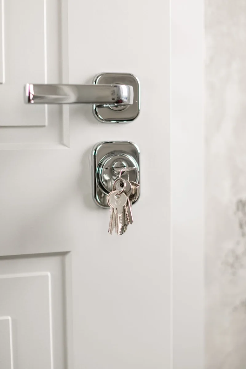 A modern door handle with keys hanging from its lock.