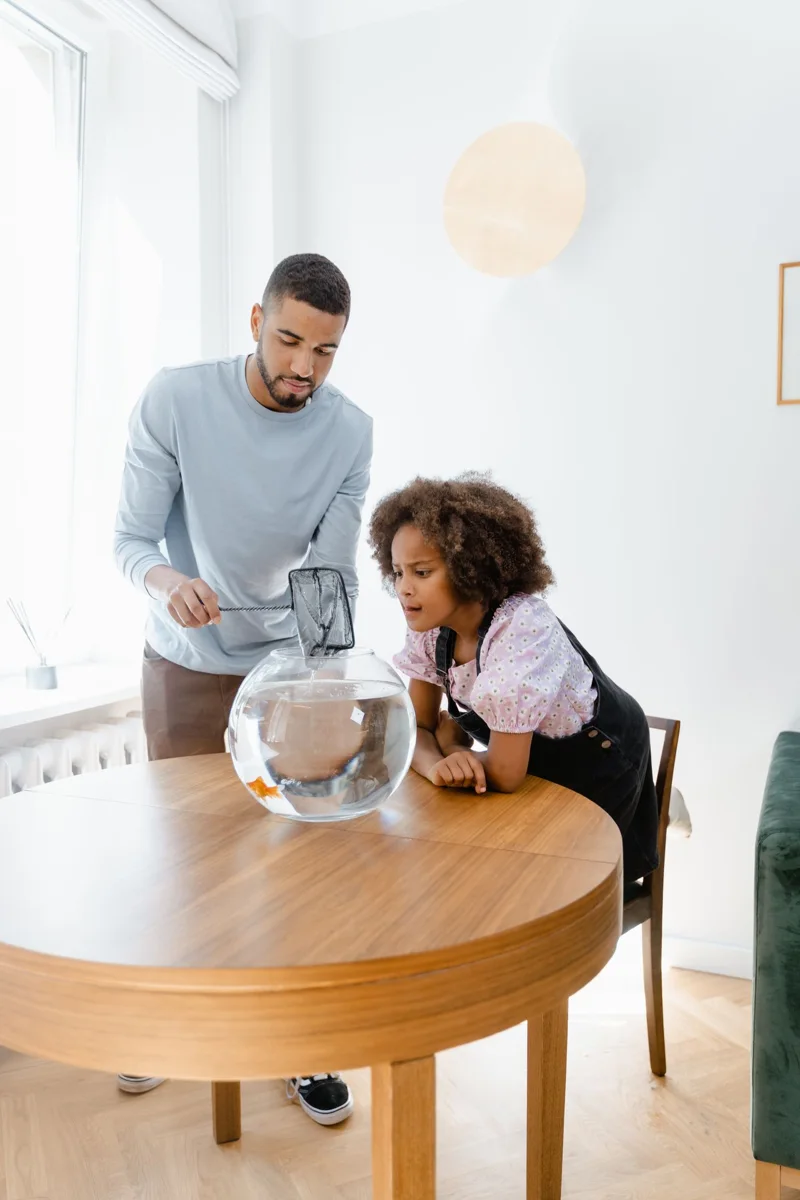 A father and daughter beside a home aquarium.