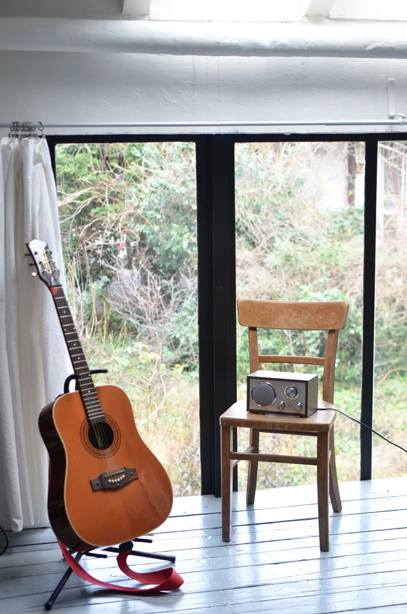 An acoustic guitar stands beside a chair in a room