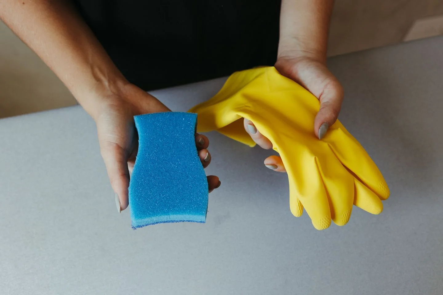 Hands holding cleaning gloves and a sponge