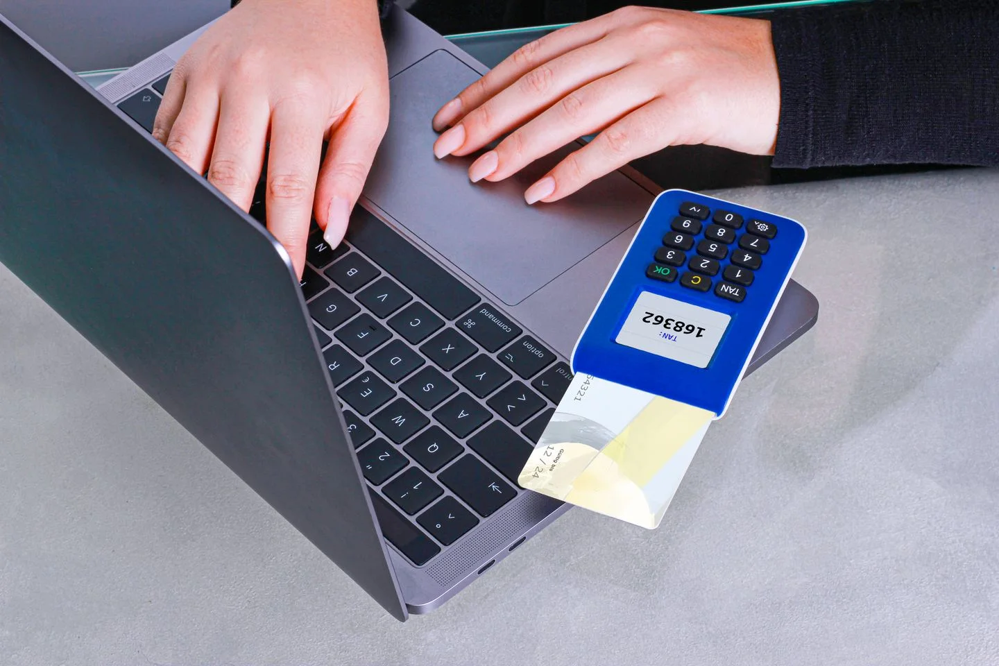 Person using a card reader beside a laptop