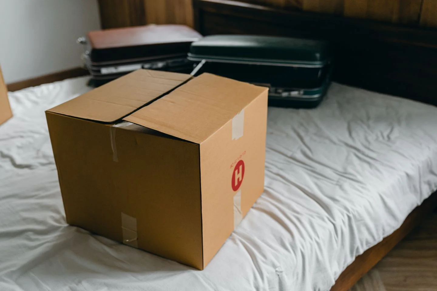 A cardboard box and suitcases on a bed