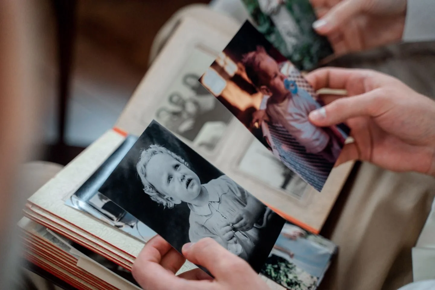 Hands examine older family photographs in an album