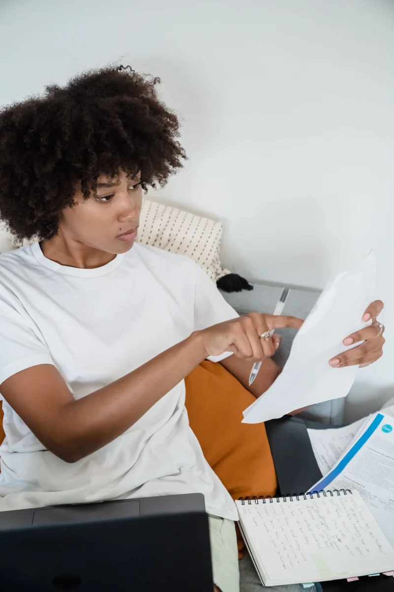 A woman compares paper documents with information on a laptop