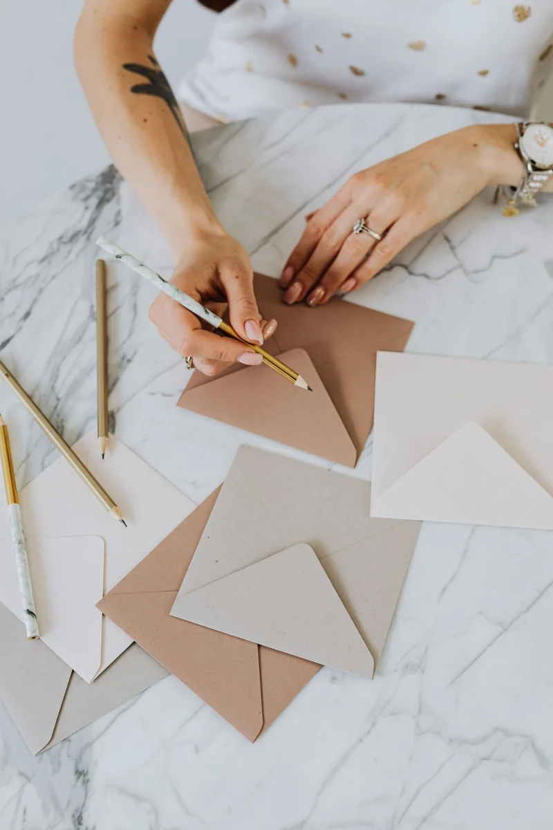 Hands write on an envelope with a pencil